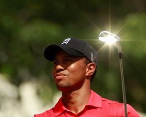 The sun reflects off the club as Tiger Woods hits off on the seventh tee during the final round...