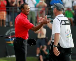 Tiger Woods celebrates with his caddie Joe LaCava after sinking his final putt on the 18th green...