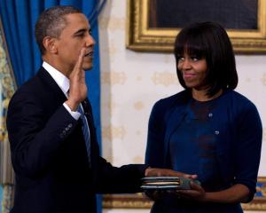 US President Barack Obama takes the oath of office as first lady Michelle Obama holds a bible...