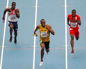 Usain Bolt of Jamaica (C) sprints to the finish line ahead of Dwain Chambers of Britain (L) and...