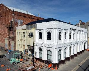 Workers enjoy a break in front of the freshly painted 131-year-old Donald Reid building, on the...