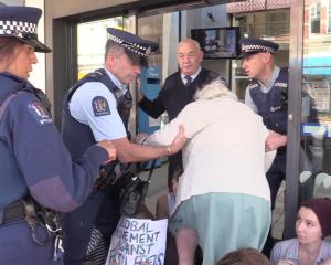 Police help an older woman to negotiate  climate change protesters blocking the entrance to an...