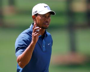 Tiger Woods holds up his ball after sinking a birdie putt on the seventh green during third round...