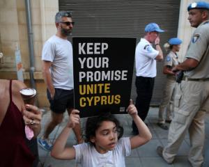 A girl holds a placard during a demonstration in favour of a peace settlement between Greek and...