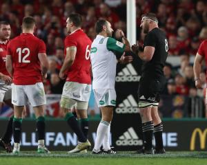 Romain Poite the referee, talks to All Black captain, Kieran Read after he reverses a decision...