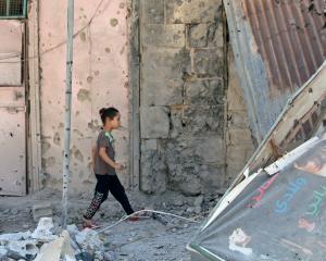 A girl walks on debris in a rebel-held part of the southern city of Deraa, Syria. Photo: Reuters