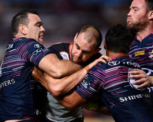 Simon Mannering of the Warriors is tackled by Te Maire Martin and Kane Linnett of the Cowboys....