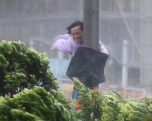 A man holds on to a lamp post as Typhoon Hato hits Hong Kong. Photo Reuters 
