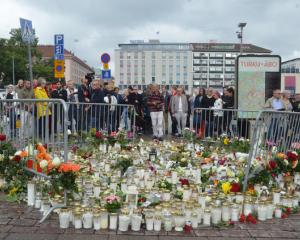 People mourn next to memorial candles and flowers at the Market Square in Turku. Photo: Reuters