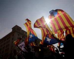 People hold on to Catalan separatist flags on top of an air vent during a demonstration two days...