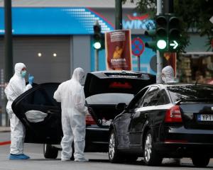 Forensics officers inspect the car of former Greek prime minister and former central bank chief...