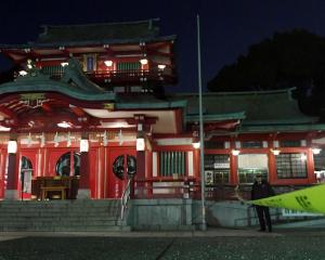 A policeman stands guard in front of the main temple of the Tomioka Hachimangu shrine in Tokyo,...