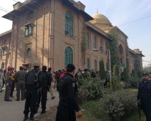 Police and rescue workers stand outside the Directorate of Agriculture Institute in Peshawar....