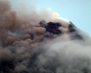 Clouds partially cover Mayon volcano's crater as it spews a column of ash during another mild...
