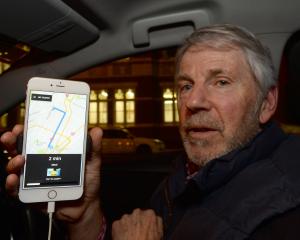 Ready to go ... Uber driver Mike Collett waits for his next fare on his phone after the San...