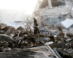 Guards walk on the wreckage of a building destroyed by air strikes in Sanaa. Photo: Reuters