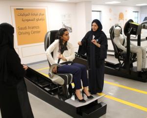 A driving instructor (R) explains seat bells to trainees Amira Abdulgader and Maria Al-Faraj (C)...
