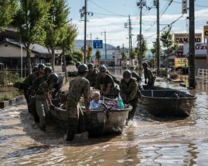 Soldiers ferry elderly people to safety following heavy flooding in Kurashiki near Okayama, Japan...