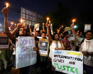 Women hold candles as they shout slogans during a protest against the rape of a ten-year-old girl...