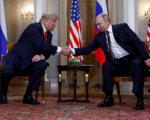 US President Donald Trump and Russia's President Vladimir Putin shake hands as they meet in...