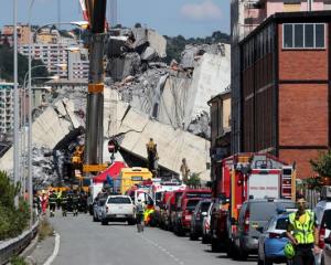 Firefighters and rescue workers stand at the site of a collapsed Morandi Bridge. Photo: Reuters