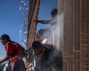 Migrants are hit by tear gas by US Customs and Border Protection after attempting to illegally...