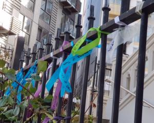 About 50 ribbons, signed with messages by victims and their supporters, were tied to the gates of...
