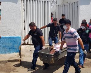 Forensic workers carry a container with a dead body after a shootout between police and bank...