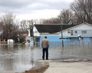 A man looks out at a flooded residential area in Gatineau, Quebec, Canada. Photo: Reuters