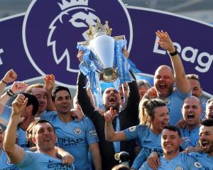 Manchester City manager Pep Guardiola lifts the trophy as they celebrate winning the Premier...
