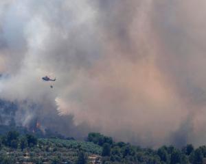 A helicopter drops water over a fire during a forest fire near Bovera, near Tarragona in Spain....