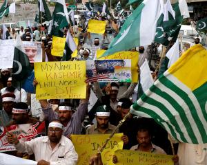 People hold flags and signs in solidarity with the people of Kashmir, during a rally in Karachi....