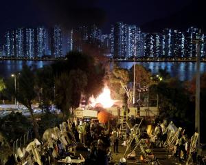 Explosives ignite an abandoned car, that were hidden there by protesters, near a barricade above...