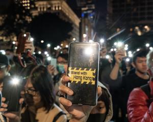 Pro-democracy supporters hold their phone flashlights at a rally to show support for students at...