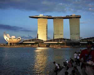 People sit on the waterfront as sunlight shines on the Marina Bay Sands resort in Singapore....
