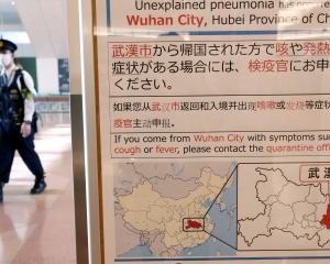 A policeman wearing a mask walks past a quarantine notice about the outbreak of coronavirus in...