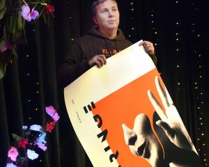 Dunedin Fringe Festival director Gareth McMillan rolls up a poster for the cancelled festival....