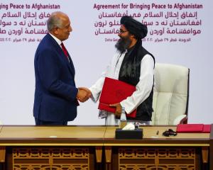Mullah Abdul Ghani Baradar, the leader of the Taliban delegation, and Zalmay Khalilzad, U.S....
