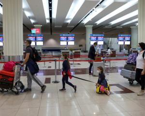 Passengers walk at Dubai International Airport as Emirates airline resumed limited outbound...