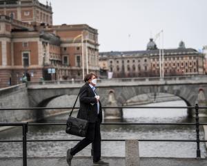 A man wearing a protective mask walks past the Royal Swedish Opera, amid the Covid-19 outbreak in...