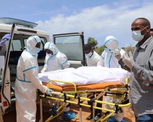 Somali workers in protective suits and civilians prepare to carry the body of a man suspected to...