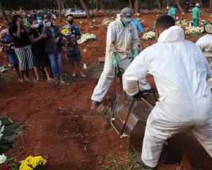 Relatives react during the burial of Geraldo Magalhaes, who died from the coronavirus disease....