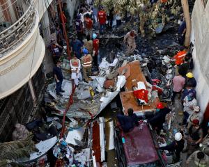 Rescue workers gather at the site of a passenger plane crash in a residential area near an...