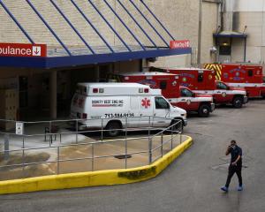 A medical worker walks past a row of ambulances parked outside of Houston Methodist Hospital as...
