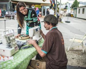 Wastebusters baler Bruce Shanks gets some bag-making advice from solar sewer Sarah Lancaster, on...