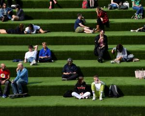 People are seen relaxing in an outdoor seating area while social distancing in London. Photo:...