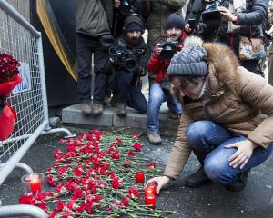 A woman lays flowers and candles and gather in front of the entrance of the Reina nightclub,...