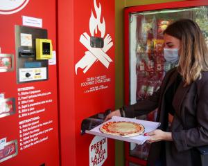 Fabrizia Pugliese collects her order at the first automatic pizza vending machine, which is...