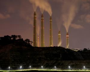 Smoke and steam billows from the coal-fired power plant owned by Indonesia Power, next to an area...