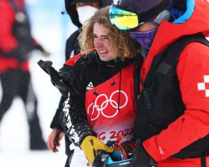 Ben Harrington reacts after crashing while being assisted by medical staff on their second run...